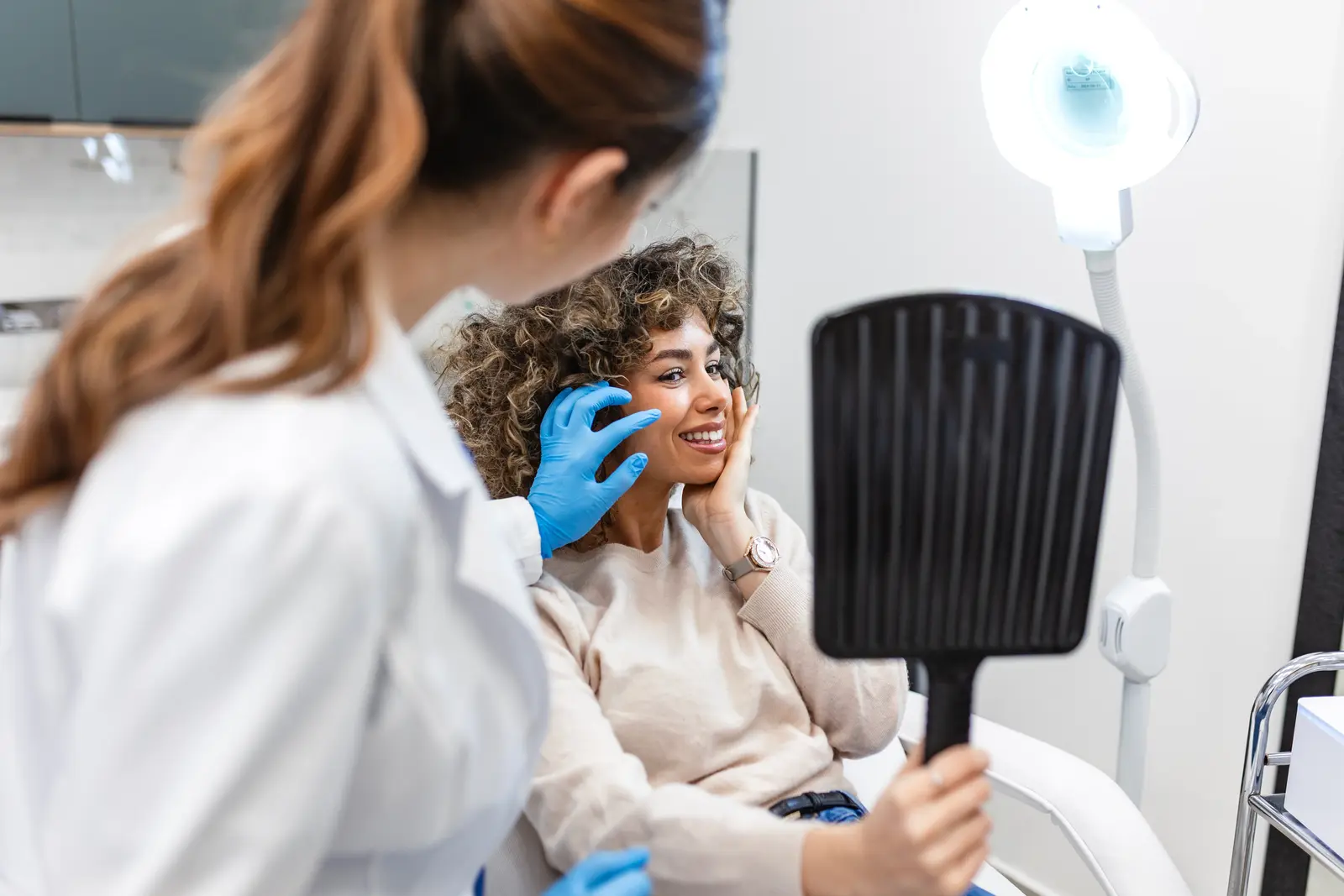 Consultation at aesthetic clinic. Woman looking in mirror.