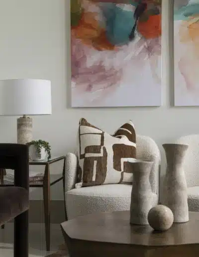 Detail shot of modern clinic lounge decor with boucle chair, throw pillow, and stone vases. Detail shot of modern clinic lounge decor with boucle chair, throw pillow, and stone vases.