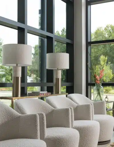 Row of cream bouclé armchairs next to large floor-to-ceiling windows with table lamps at Elite Dermatology. Row of cream bouclé armchairs next to large floor-to-ceiling windows with table lamps at Elite Dermatology.