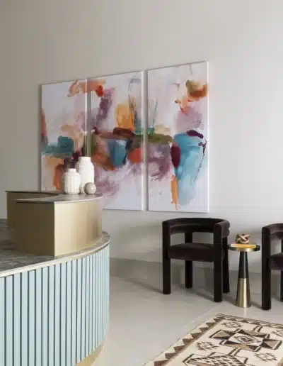 Side angle of curved fluted reception counter alongside velvet chairs and triptych abstract art. Side angle of curved fluted reception counter alongside velvet chairs and triptych abstract art.