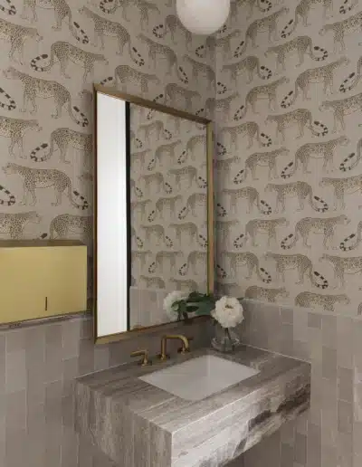 Luxury clinic restroom with a marble floating sink, gold faucet, mirror, and cheetah wallpaper. Luxury clinic restroom with a marble floating sink, gold faucet, mirror, and cheetah wallpaper.