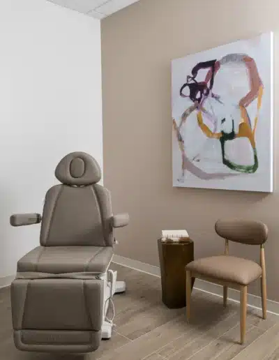 Medical procedure room with taupe treatment chair, consultation seat, and abstract art. Medical procedure room with taupe treatment chair, consultation seat, and abstract art.
